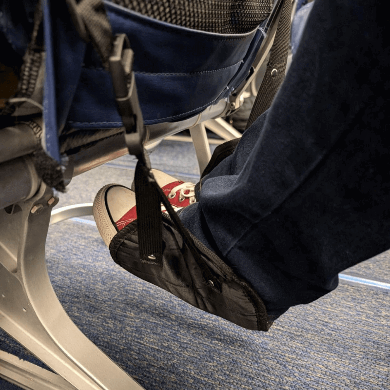 Airplane Footrest hammock supporting feet mid-flight for improved comfort and circulation.